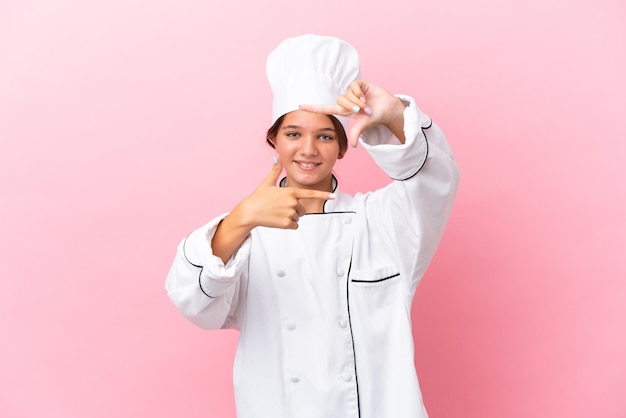 Petite fille de chef caucasien isolée sur fond rose se concentrant sur le visage Symbole de cadrage