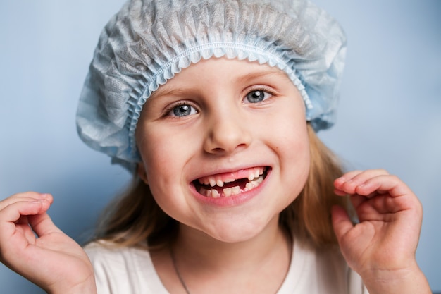 Une petite fille chez le dentiste montre une bouche édentée.