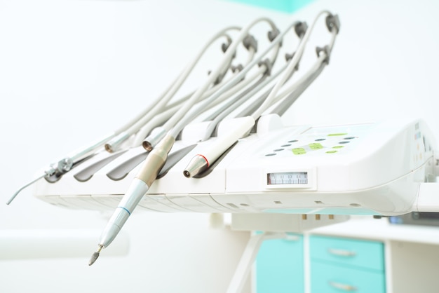 Petite Fille Chez Le Médecin. Le Dentiste Place Un Remplissage Sur Une Dent Avec Une Lampe De Polymérisation Dentaire Dans La Cavité Buccale. Sur Fond De Clinique