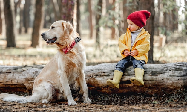 Petite fille avec chien golden retriever dans la forêt