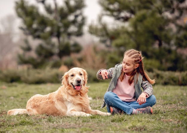 Petite fille avec un chien golden retriever à l'extérieur