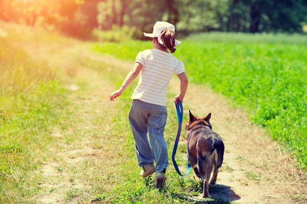 Petite fille avec chien marchant sur la route