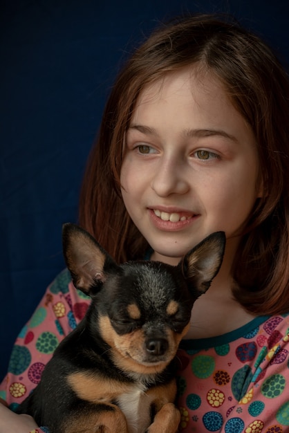 Petite fille avec un chihuahua. Fille tenant chihuahua. Fille avec son animal de compagnie dans ses bras. Chihuahua de couleur blanc brun noir. Les enfants adorent leurs animaux. Fille et chihuahua. Les enfants adorent leurs animaux