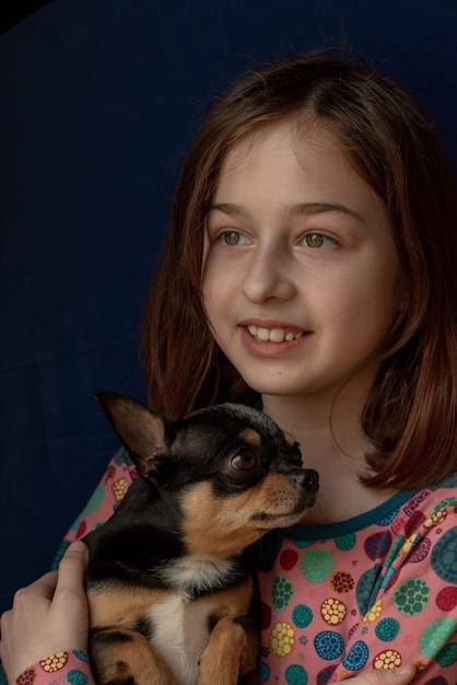 Petite fille avec un chihuahua. Fille tenant chihuahua. Fille avec son animal de compagnie dans ses bras. Chihuahua de couleur blanc brun noir. Les enfants adorent leurs animaux. Fille et chihuahua. Les enfants adorent leurs animaux