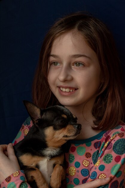 Petite fille avec un chihuahua. Fille tenant le chihuahua. Fille avec son animal de compagnie dans ses bras.