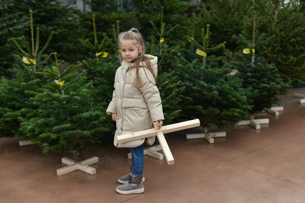 La petite fille choisit un arbre de Noël sur le marché.