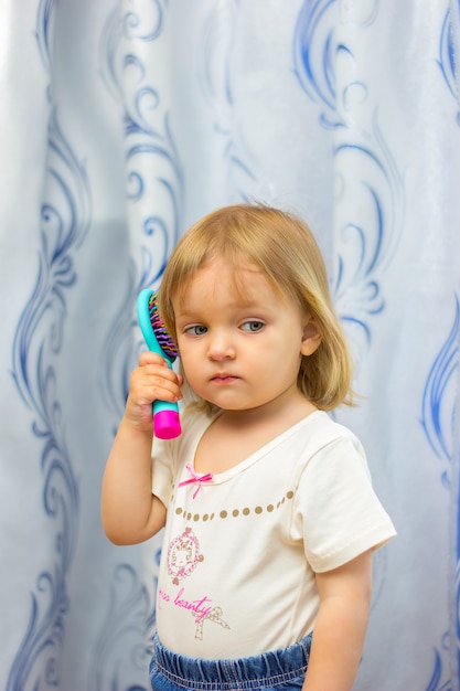 La petite fille coiffe une brosse à cheveux