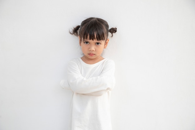 Petite fille en colère sur fond blanc, signe et concept de geste
