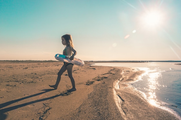 Petite fille en colère quitte la mer, ne veut pas nager dans l'eau froide. Espace de copie. Photo tonique.