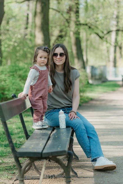 Une petite fille en combinaison de velours est sur le banc avec sa mère