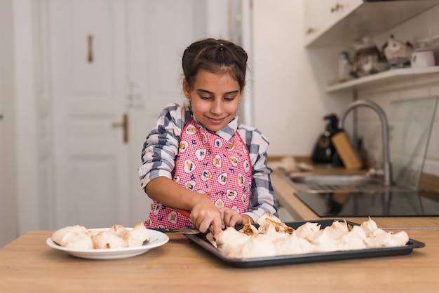 Petite fille cookies sur une plaque de cuisson.