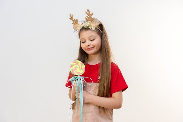 Une petite fille avec des cornes de Noël est heureuse du prochain Noël.