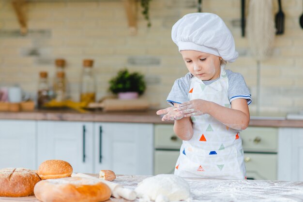 Petite fille en costume de chef cuisinier dans la cuisine