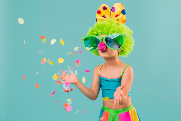 Petite fille en costume de clown avec des confettis