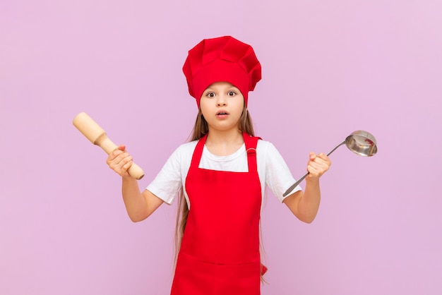 Une petite fille en costume de cuisinier avec une louche sur un fond isolé