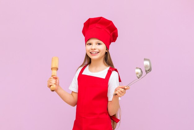 Une petite fille en costume de cuisinier avec une louche sur un fond isolé