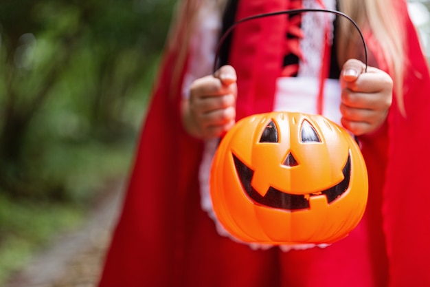 Petite fille en costume d'Halloween tenant la citrouille