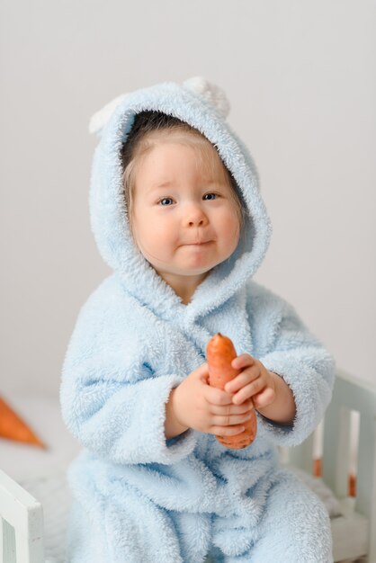 Petite fille en costume de lapin mangeant des carottes.