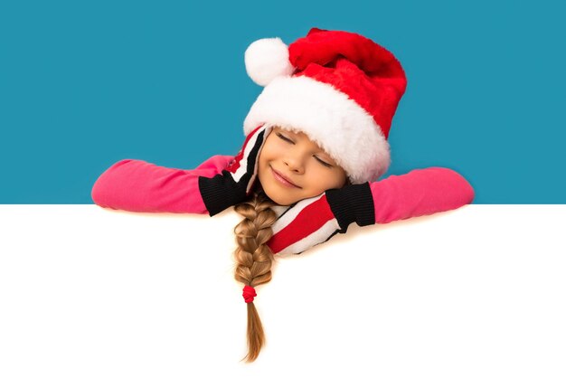 Une petite fille en costume de Noël s'est endormie sur un tableau blanc