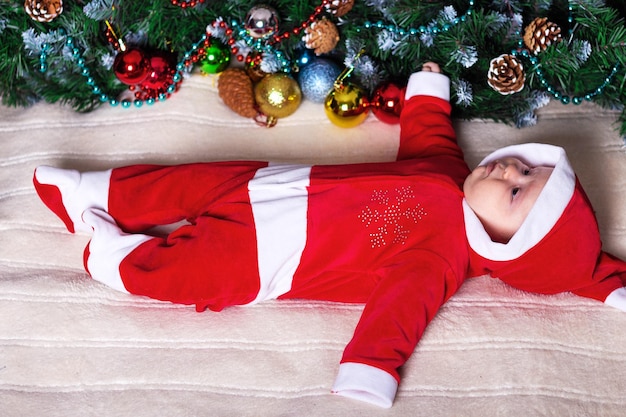 Petite fille en costume de Père Noël allongée sur une couverture