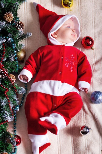 Petite fille en costume de Père Noël allongée sur une couverture