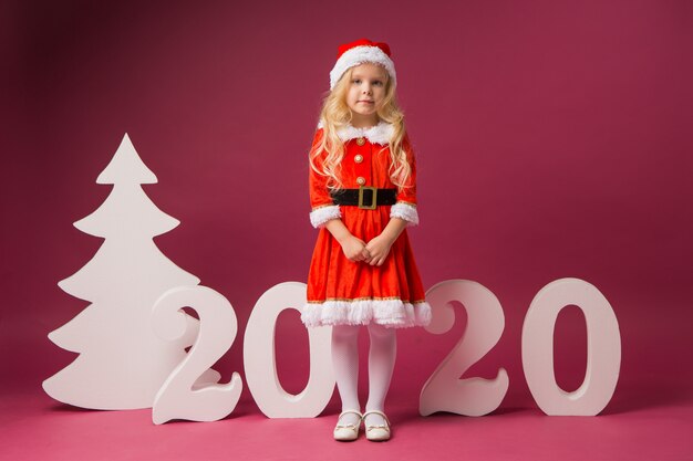 Petite fille en costume de Père Noël avec des numéros 2020