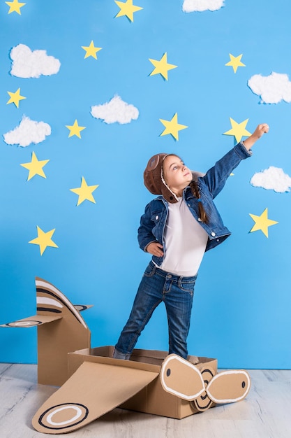 Une petite fille en costume de pilote joue et rêve de voler au-dessus des nuages.