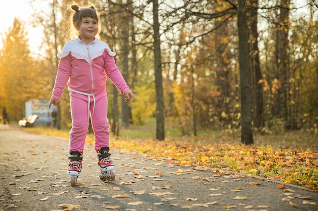 Une petite fille en costume rose à cheval sur des rouleaux