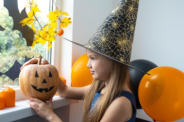 Petite fille en costume de sorcière avec citrouille se préparant pour la fête d'Halloween. Concept de décoration de vacances