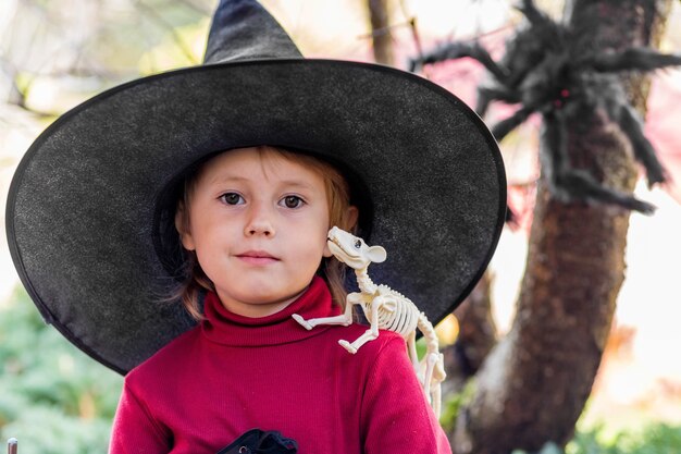 Petite Fille En Costume De Sorcière Faisant Des Visages Différents Sur La Fête D'halloween Dans Le Jardin