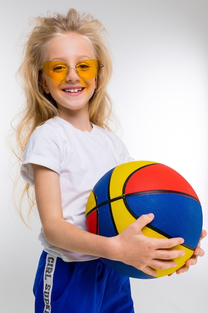 Petite fille en costume de sport avec basket-ball isolé