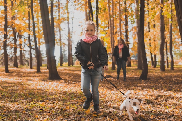 Petite fille courir avec son chien jack russell terrier parmi les feuilles d'automne mère et grand-mère wal