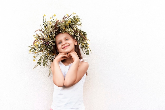 Petite fille avec une couronne de fleurs sauvages sur fond blanc