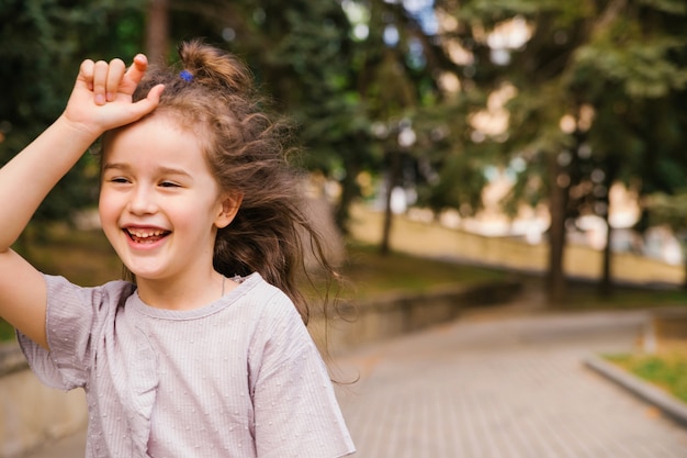 Une petite fille court le long du trottoir du parc. Jeu actif dans la nature. La fille rit et est heureuse.