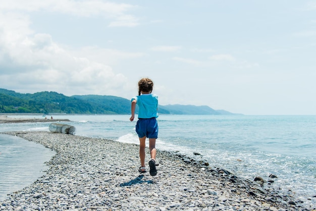 Une petite fille court le long de la plage Été