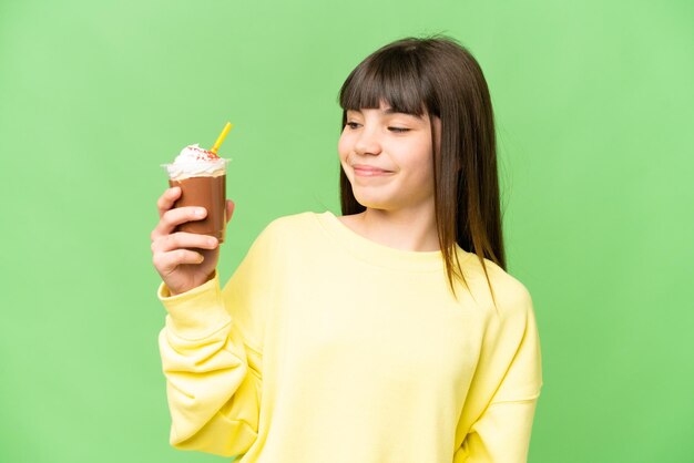 Petite fille avec de la crème au chocolat sur fond isolé chroma key avec une expression heureuse