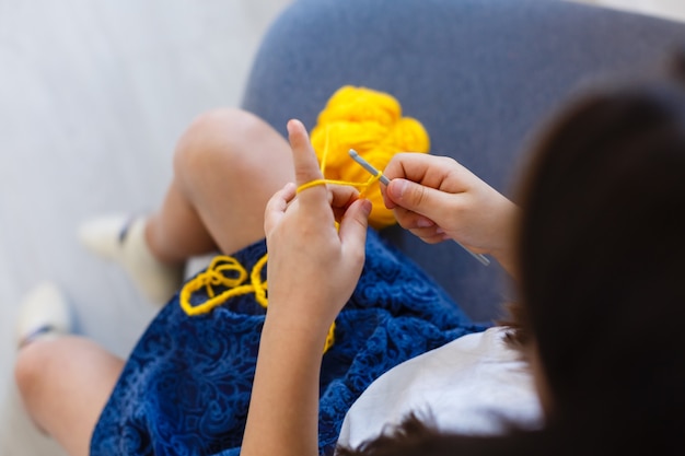 petite fille crochets avec des fils jaunes. Vue de dessus. Faire de la décoration.