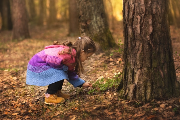 petite fille cueille les premières fleurs du printemps dans la forêt