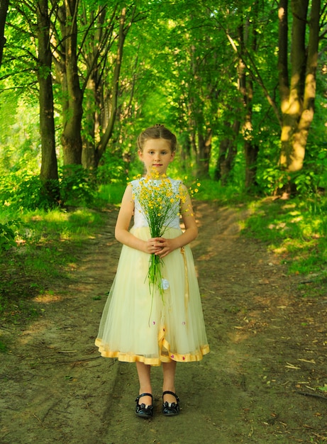 Petite fille dans les bois avec un bouquet de fleurs sauvages