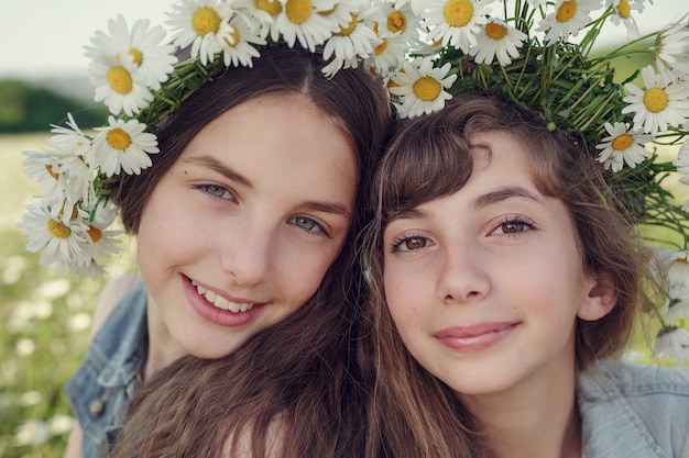 Petite fille dans un champ de fleurs de marguerite. Filles dans une couronne de marguerites blanches, le concept et l'idée d'une enfance heureuse