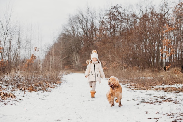 Petite fille dans les champs d'hiver entouré de chien cocker spaniel