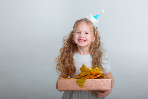 Petite fille dans un chapeau d'anniversaire tenant un cadeau