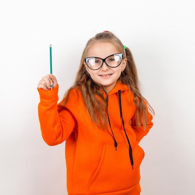 Une petite fille dans un costume orange lunettes et crayon Le concept d'autodéveloppement de la formation scolaire Sur fond blanc