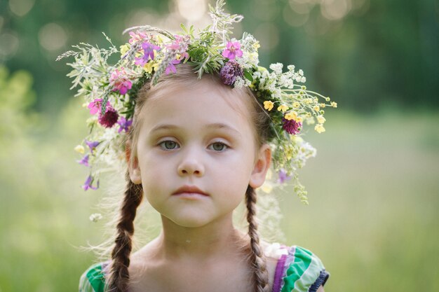 petite fille dans une couronne de fleurs sauvages en été