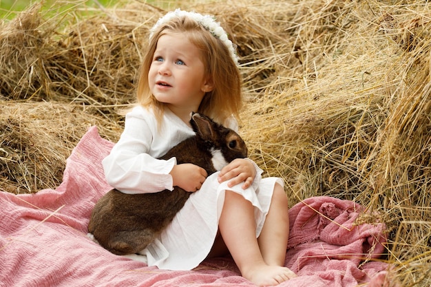 Petite fille dans la crèche dans un lapin en robe blanche