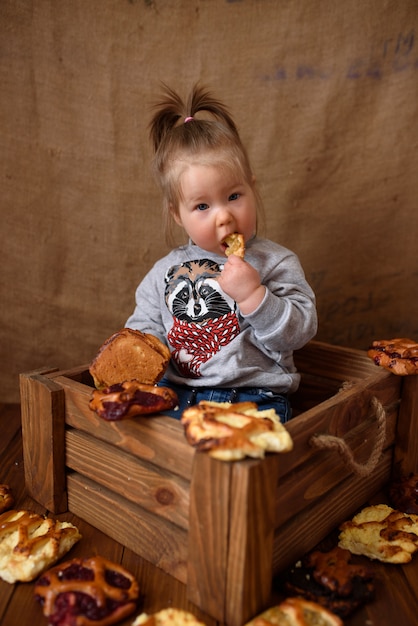 Petite fille dans la cuisine mange des pâtisseries sucrées.