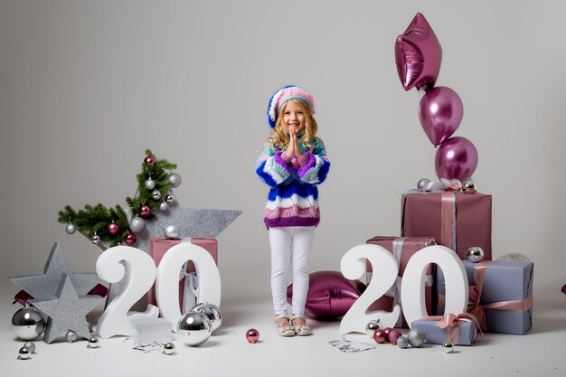 petite fille dans un décor de vacances à la lumière, coffrets cadeaux, grands nombres 2020, nouvel an et Noël