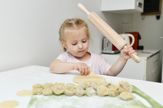 La petite fille dans la farine prépare les boulettes