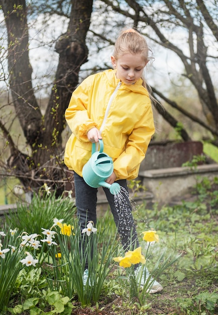 Petite fille dans un jardin avec arrosoir vert