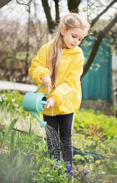 Petite fille dans un jardin avec arrosoir vert